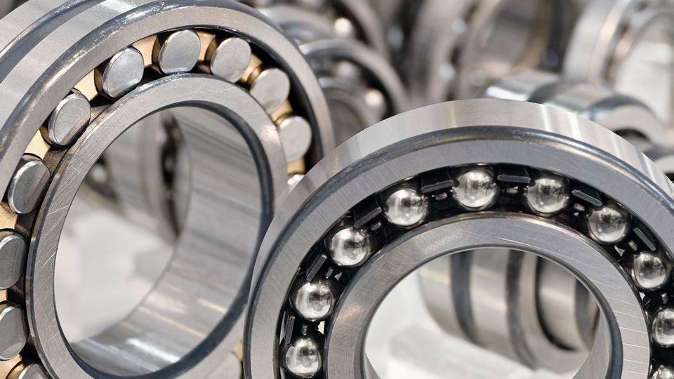 Close-up of multiple ball bearings and roller bearings, showcasing their metallic construction and circular design.