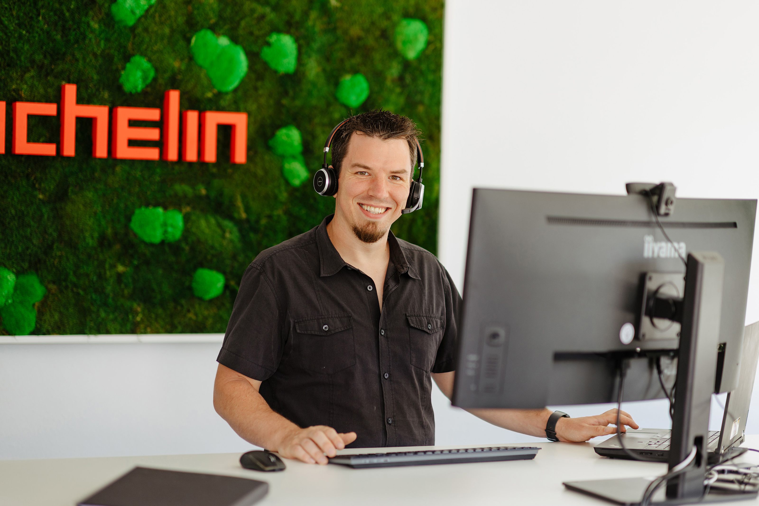 Mann steht mit Heatset am Computer
