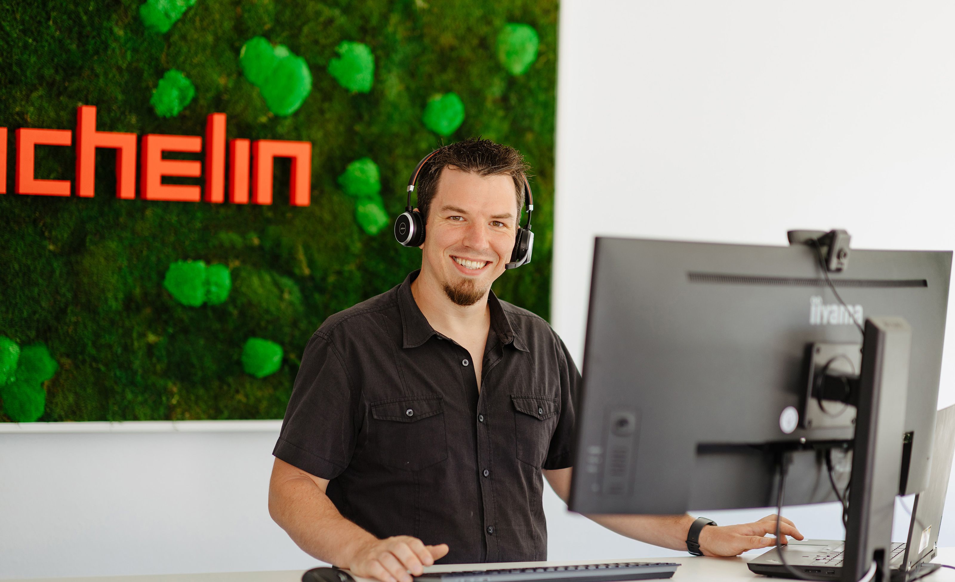 Mann steht mit Heatset am Computer